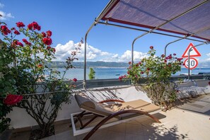 Une terrasse avec un fauteuil de relaxation, une vue sur la mer et un panneau indiquant la limite de vitesse.