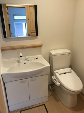 A bathroom with a white sink, mirror, and toilet.
