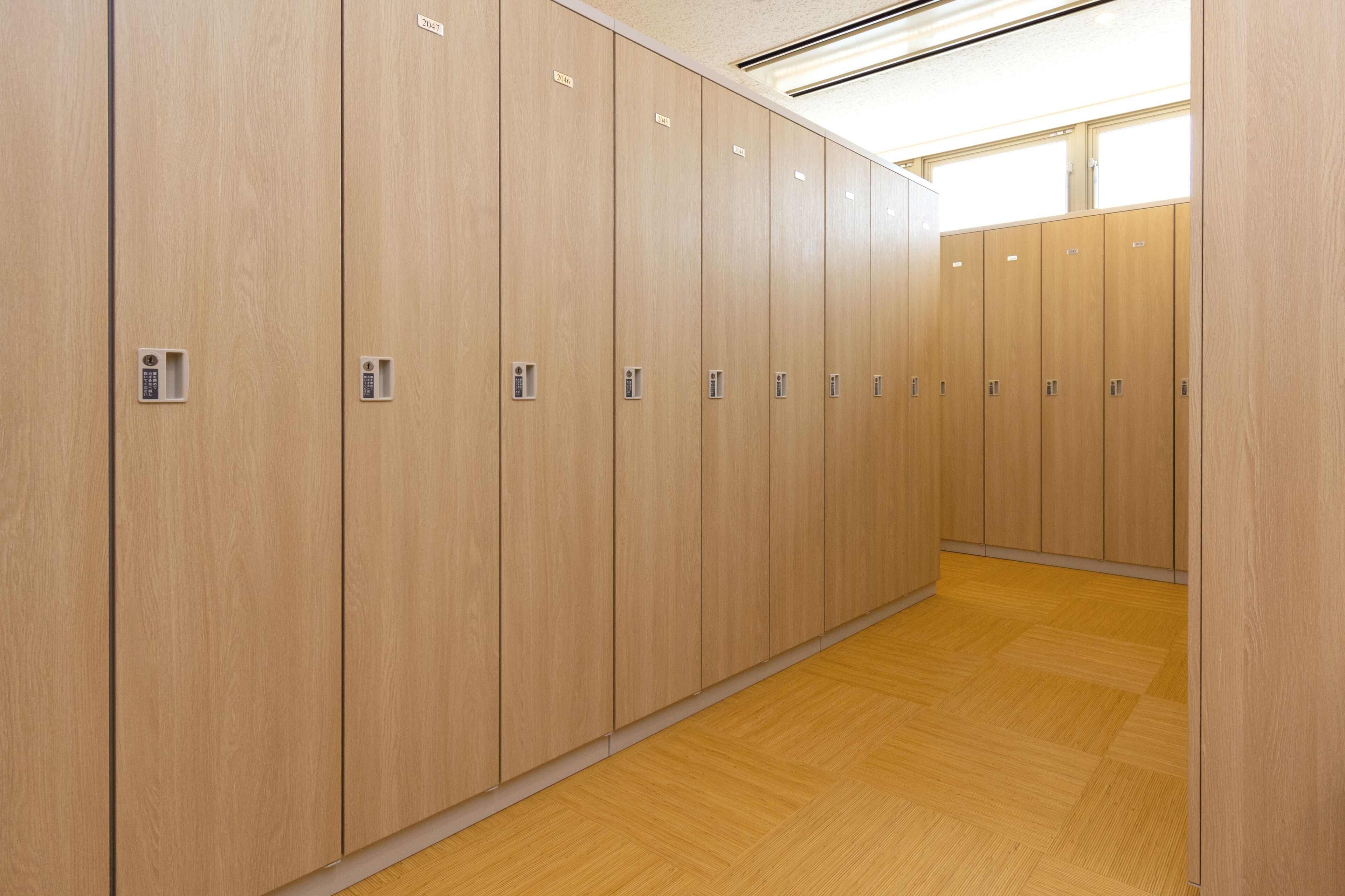 A row of wooden lockers with metal handles and a wooden floor.