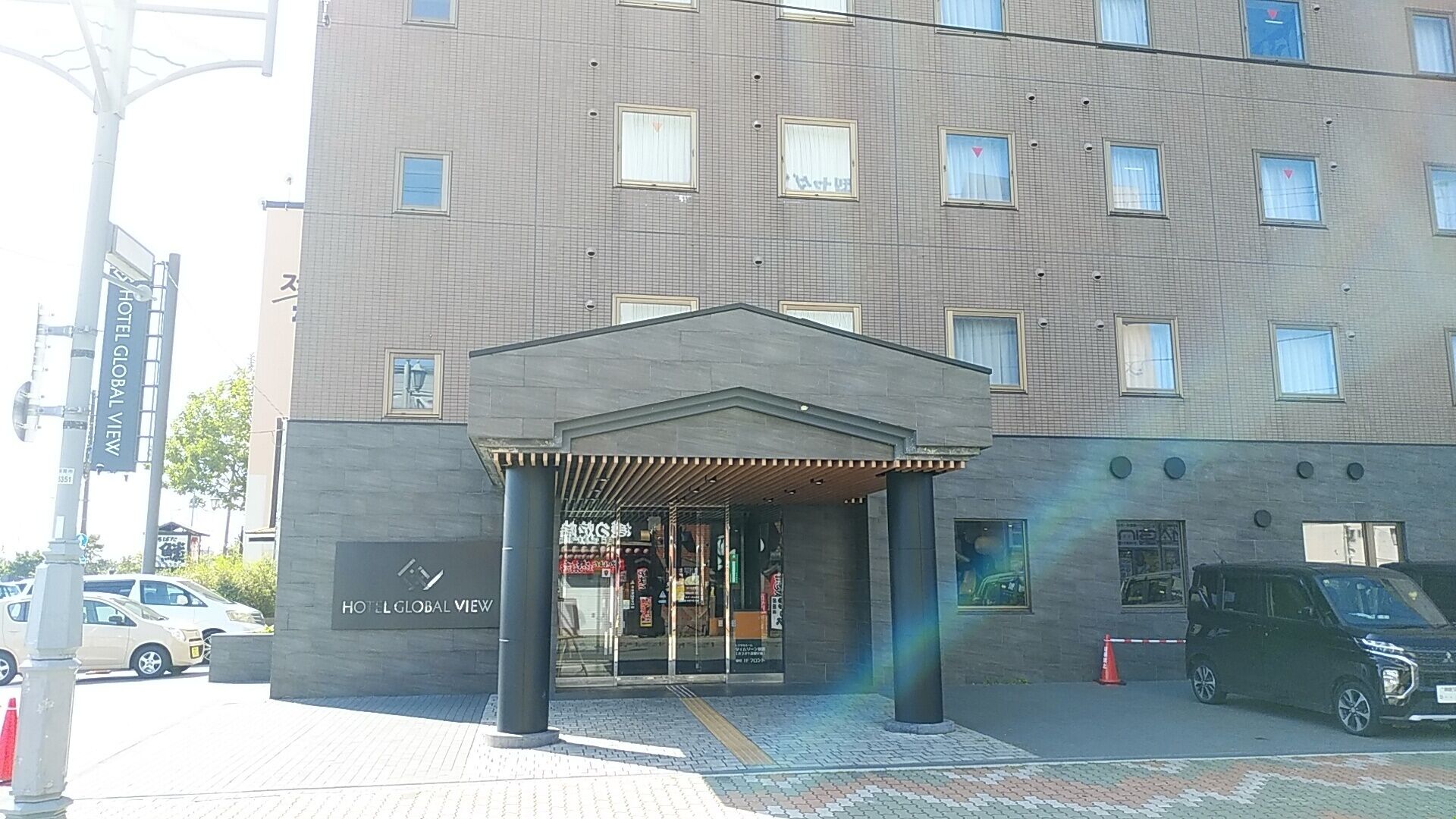 A hotel entrance with a covered entrance, a sign for Hotel Global View, and a modern building facade.