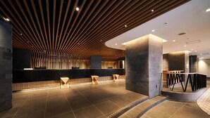 A modern lobby with a wooden slatted ceiling, a reception desk, and a stone-tiled floor. - HOTEL GLOBAL VIEW KUSHIRO (Kushiro)