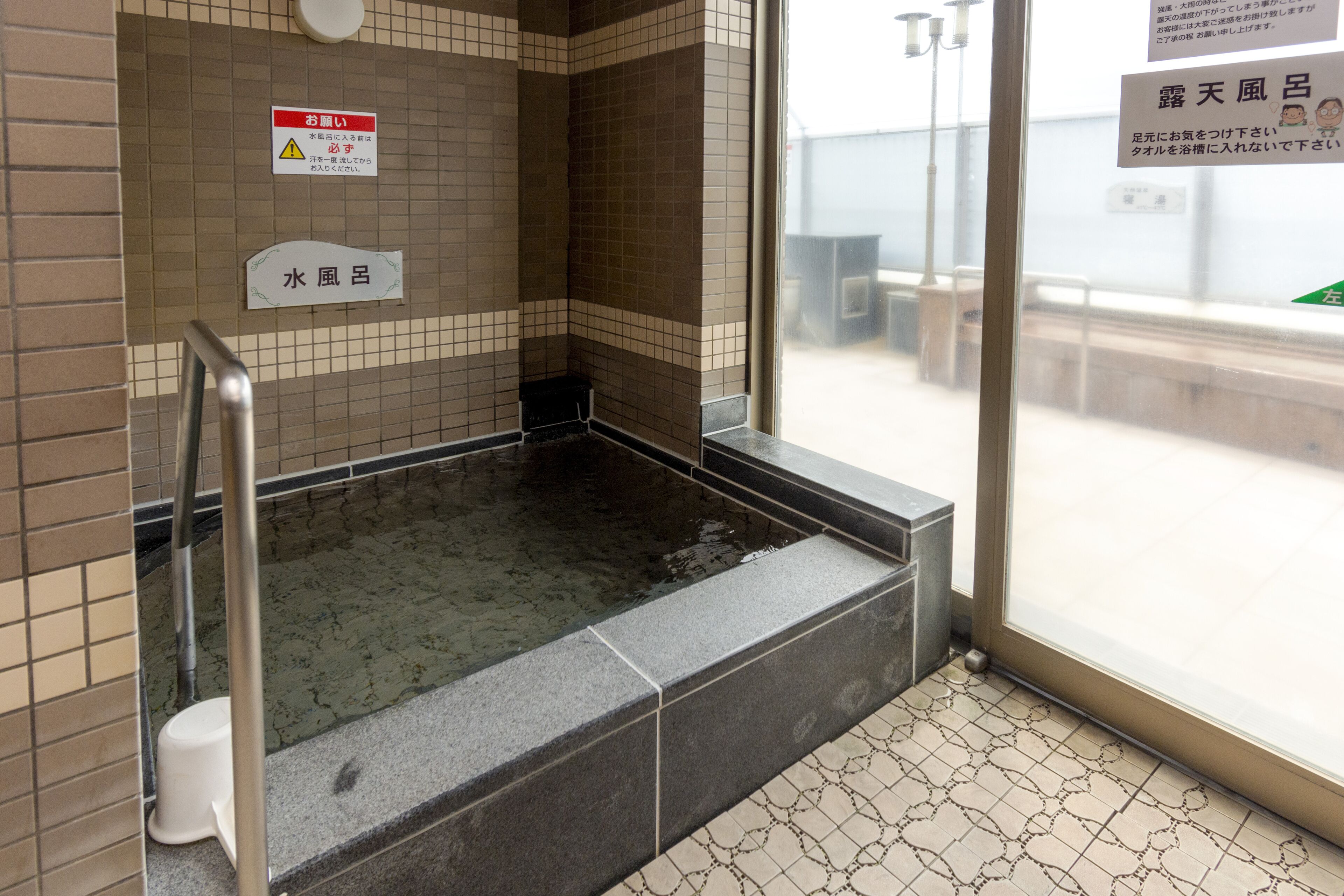 A hot spring bath area with tiled walls and a tiled floor.