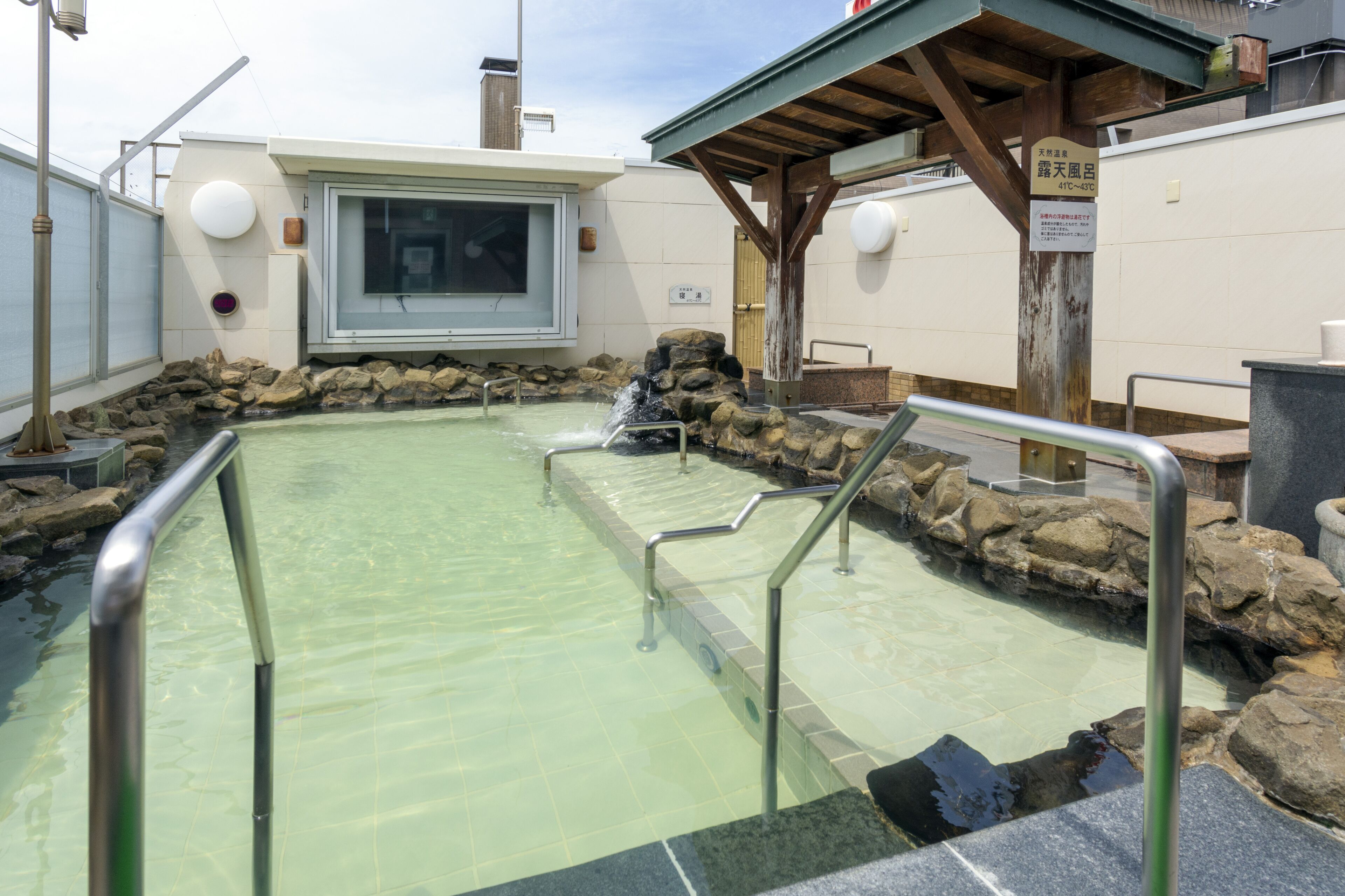Bagno termale con pareti in pietra e ringhiere in metallo.