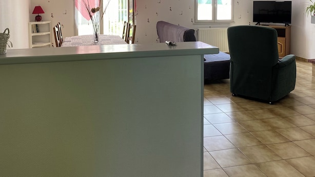 Un amplio espacio de estar con un ventanal grande, un sofá, un televisor y una mesa de comedor.