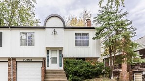 A two-story house with a white exterior, a garage, and a front door.