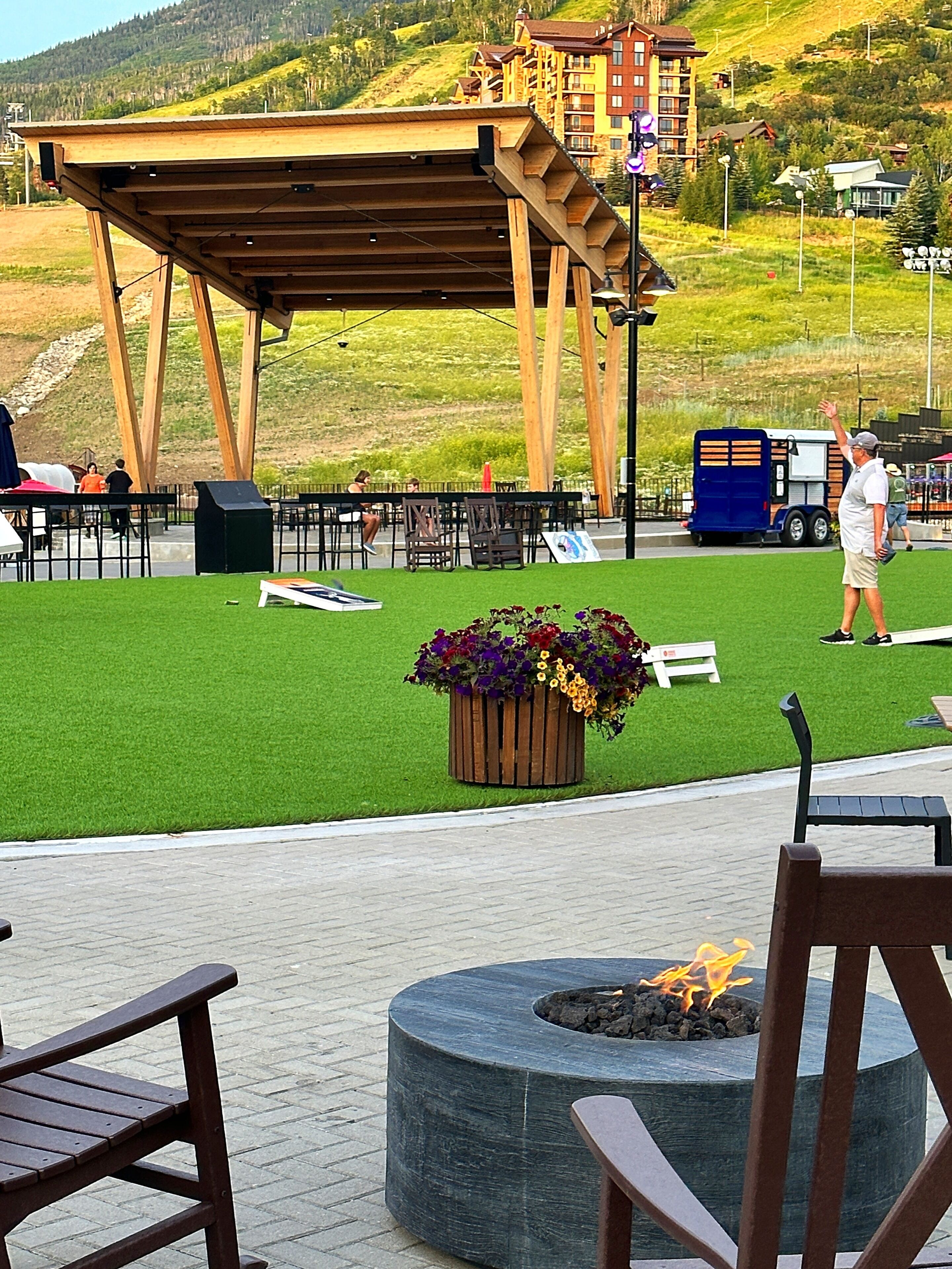 A covered outdoor seating area with a fire pit and a planter with flowers.