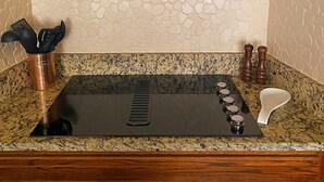 A kitchen with a granite countertop, a black sink, and a backsplash with a stone-like pattern.