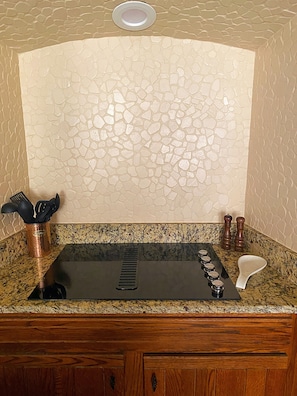 A kitchen with a granite countertop, a black sink, and a backsplash with a stone-like pattern.
