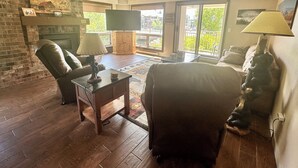 A living room with a fireplace, leather chairs, a coffee table, and a television.
