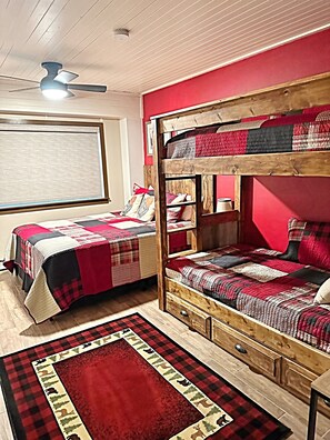 A bunk bed room with a red wall, a ceiling fan, and a window with blinds. - Stay just steps from the Gondola! (Steamboat Springs)