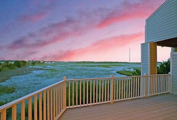 A wooden deck with a railing overlooking a water body and a distant landscape.