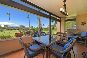 A balcony with wicker furniture, a glass table, and a view of a golf course. - Amazing Views 2BR 2BA AC Pool Wlak to Beach Sleeps 6 - Kaanapali Royal N102 (Lahaina)
