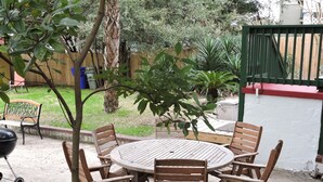 Un patio al aire libre con una mesa redonda de madera y seis sillas.