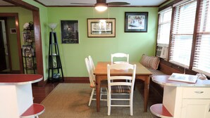 Un comedor con una mesa y sillas de madera, un tapete y una ventana con persianas.