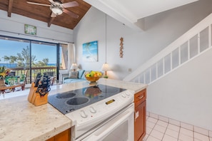 Enjoy cooking in this well-equipped kitchen with a stove, oven, and granite countertop, offering a view of the outdoors.