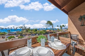 Enjoy a meal on the balcony with a view of the ocean and palm trees.