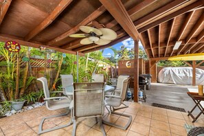 Enjoy dining and socializing in this serene outdoor space surrounded by lush greenery and a barbecue grill.