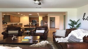 A spacious living room with leather sofas, a coffee table, and a kitchen in the background. - RELAXING INDIAN PALMS HOME WALK TO POLO FIELDS, PRIVATE POOL! ON GOLF COURSE (Indio)