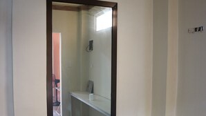 A room with a white wall, a black-framed door, a white bench, and a tiled floor. - Brown Epitome Lodge (Baler)