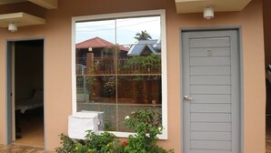 A building with a large window, a door, and a small covered area with plants. - Brown Epitome Lodge (Baler)