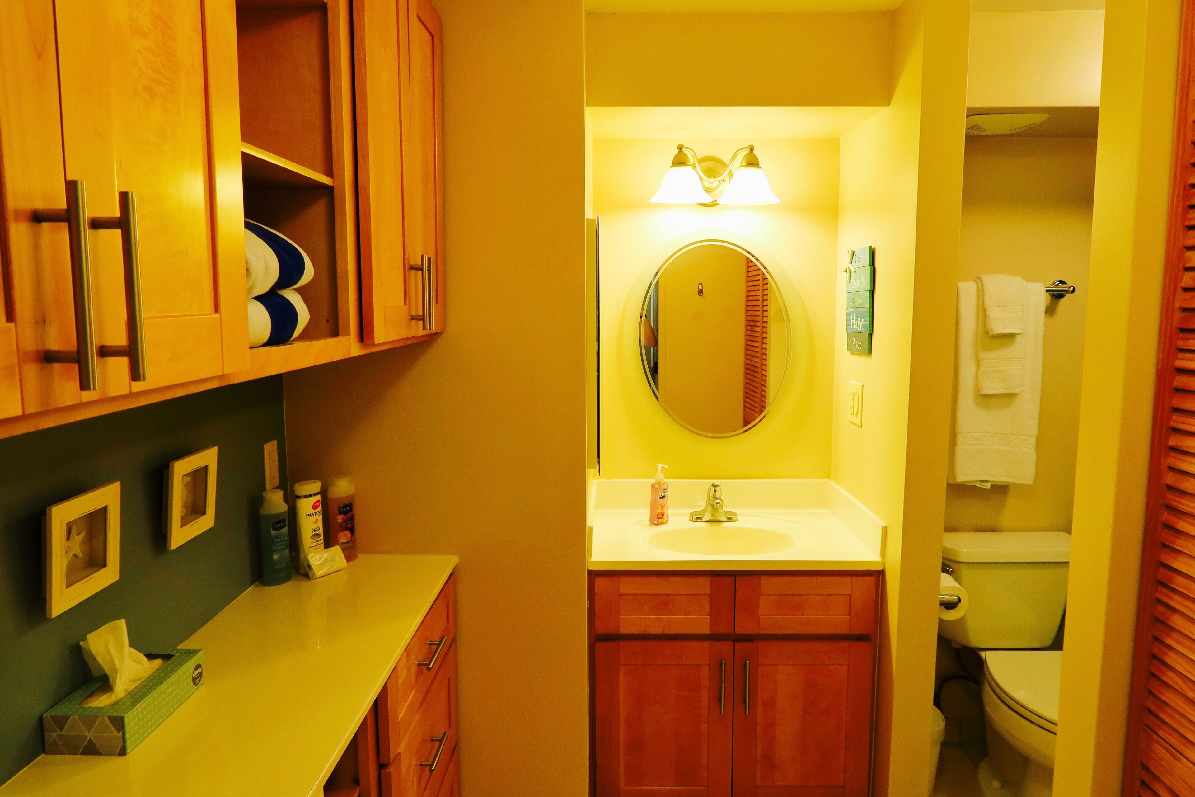 A bathroom with wooden cabinets, a sink, a mirror, and a toilet.