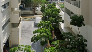 Un edifici residencial de diverses plantes amb balcons, una zona d'aparcament i vegetació als voltants.