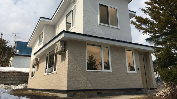 A two-story building with a flat roof, large windows, and a satellite dish. - Bliss & Bless Furano (Furano)