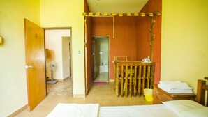 A room with a bed, a small table, a fan, and a chair. - G.T. Guest House (Saipan)
