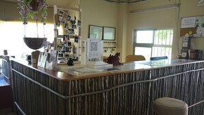 A reception area with a counter, a QR code, a bulletin board, and a window. - G.T. Guest House (Saipan)