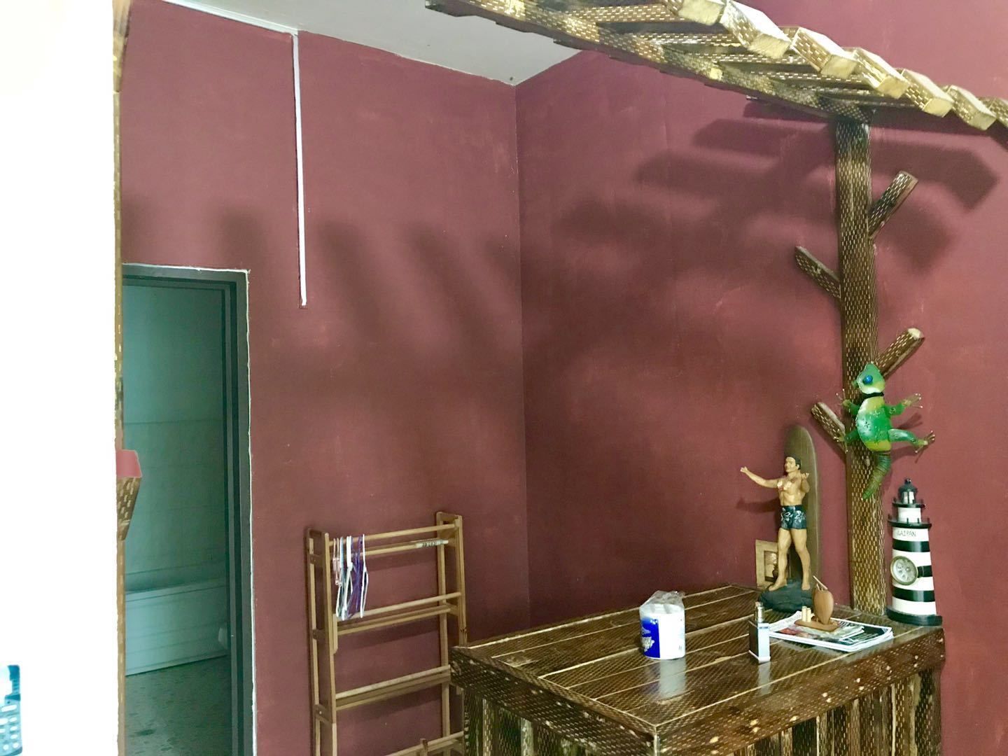 Une pièce avec une table en bois, une chaise, une petite étagère et un arbre décoratif orné d’une figurine de grenouille.