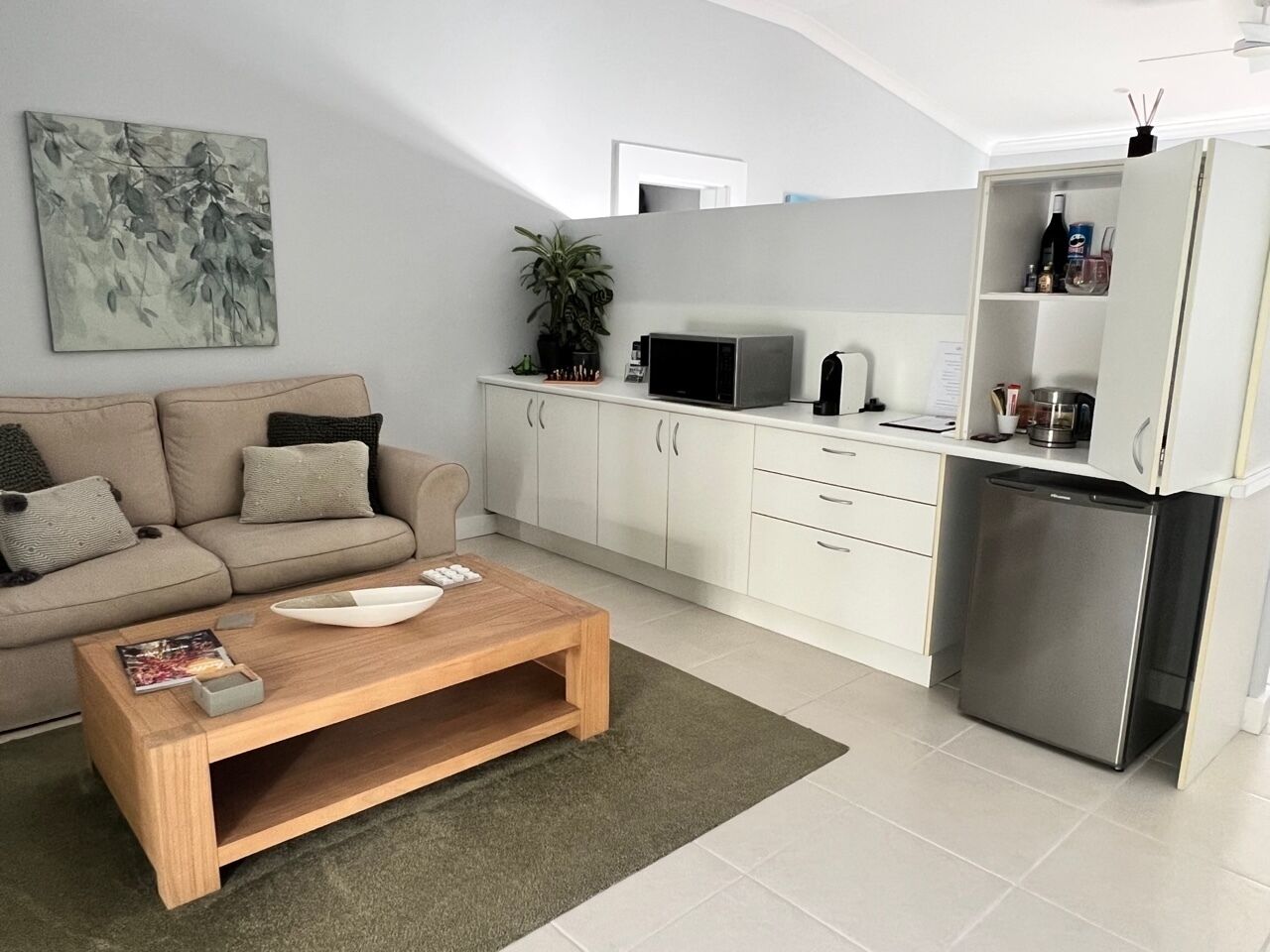 A modern kitchen with white cabinets, a stainless steel refrigerator, and a wooden coffee table.