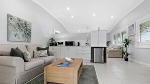 A modern living room with a sofa, coffee table, and a kitchen area in the background. - The Country House at Hunchy Montville (Hunchy)