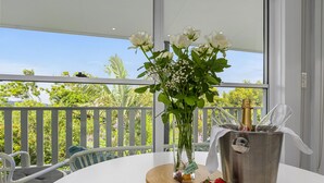 A table with a vase of white flowers, a glass bowl of strawberries, and a champagne bucket on a balcony with a view of greenery. - The Country House at Hunchy Montville (Hunchy)