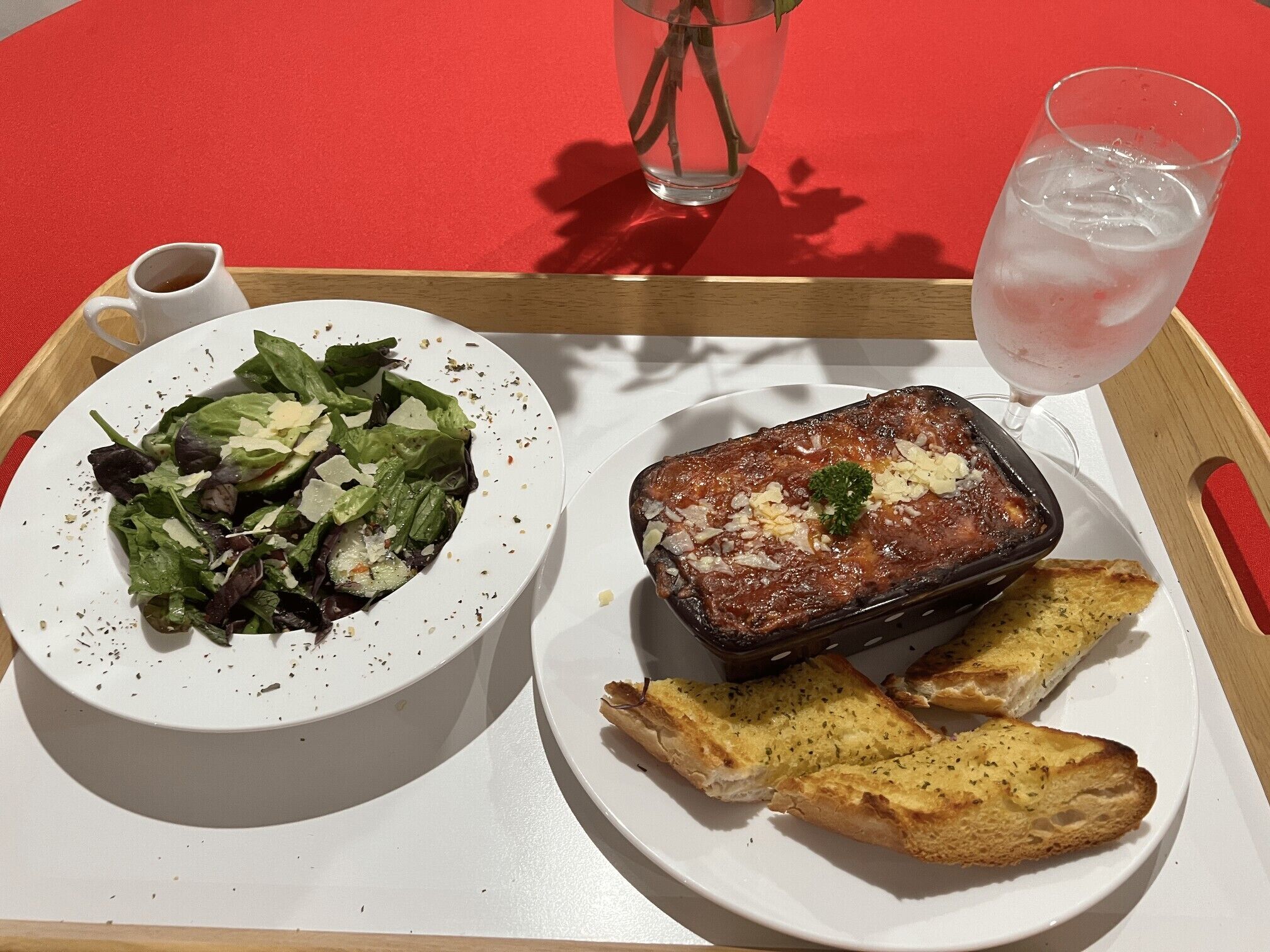 Un plateau avec une assiette de viande rôtie, une salade en accompagnement et du pain à l’ail.