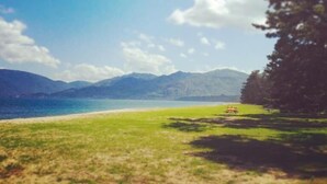 A beach with a clear sky, grassy area, and mountains in the background. - Amanohashidate Youth Hostel (Miyazu)