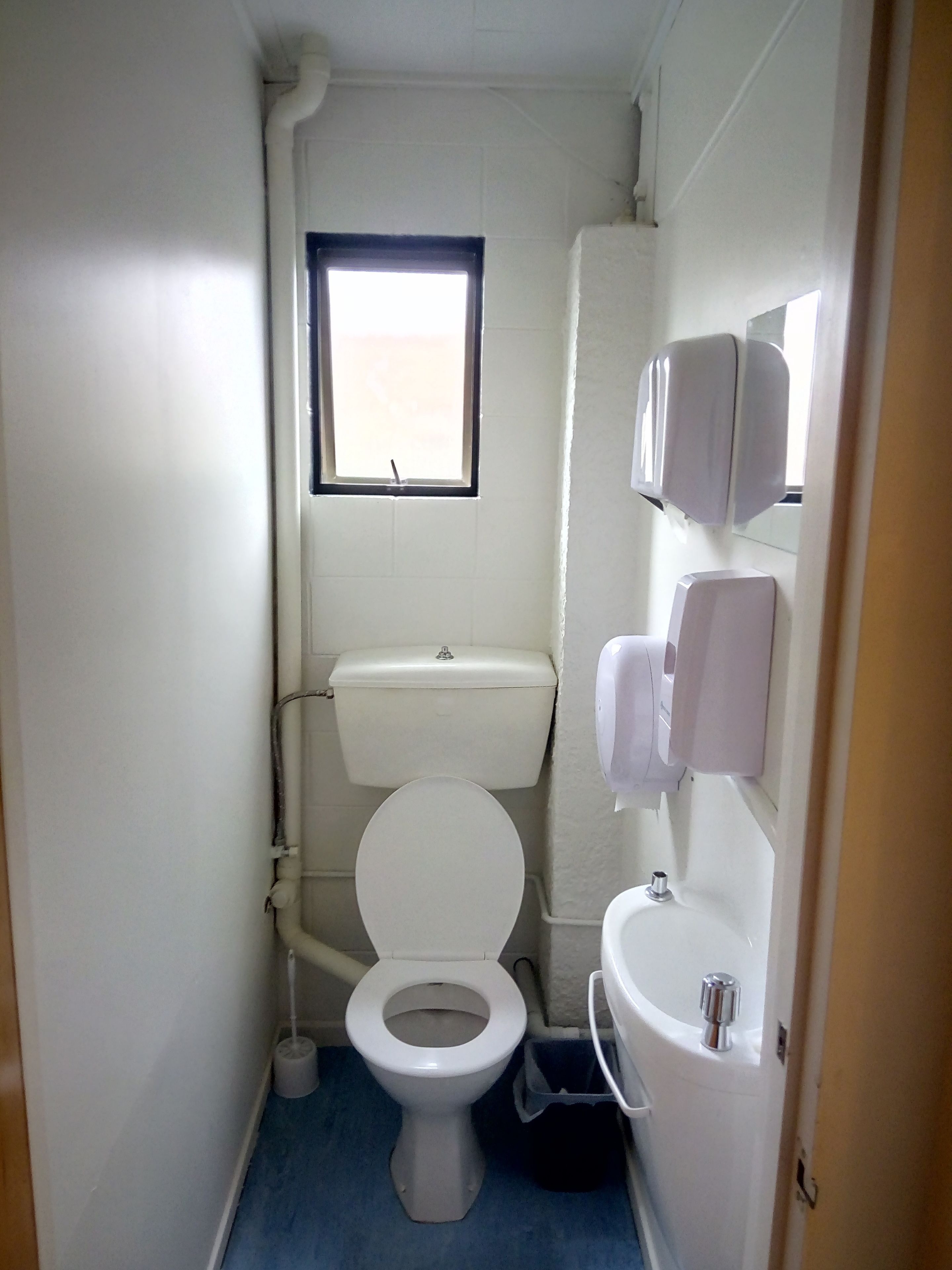 Un baño pequeño y funcional con inodoro, bidé y lavamanos.