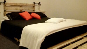 Un lit avec une tête de lit en bois, une literie noire et blanche et des oreillers orange.