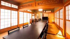 A traditional Japanese-style room with tatami flooring, sliding doors, and a long table.