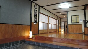A traditional Japanese interior with tatami flooring, sliding doors, and a wooden bench.