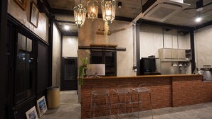 A bar area with a brick counter, metal stools, and pendant lighting. - VILLA23 Residence (Bangkok)