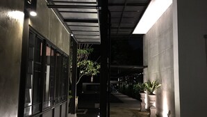 A narrow corridor with a covered walkway, potted plants, and a staircase leading to an upper level. - VILLA23 Residence (Bangkok)