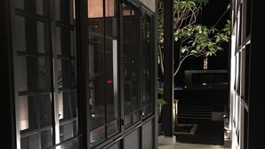 A corridor with large windows and a concrete floor, leading to a building entrance. - VILLA23 Residence (Bangkok)