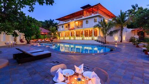 A large house with a swimming pool, outdoor seating, and a well-lit patio area. - Golden Tulip Goa Mandrem (Mandrem)