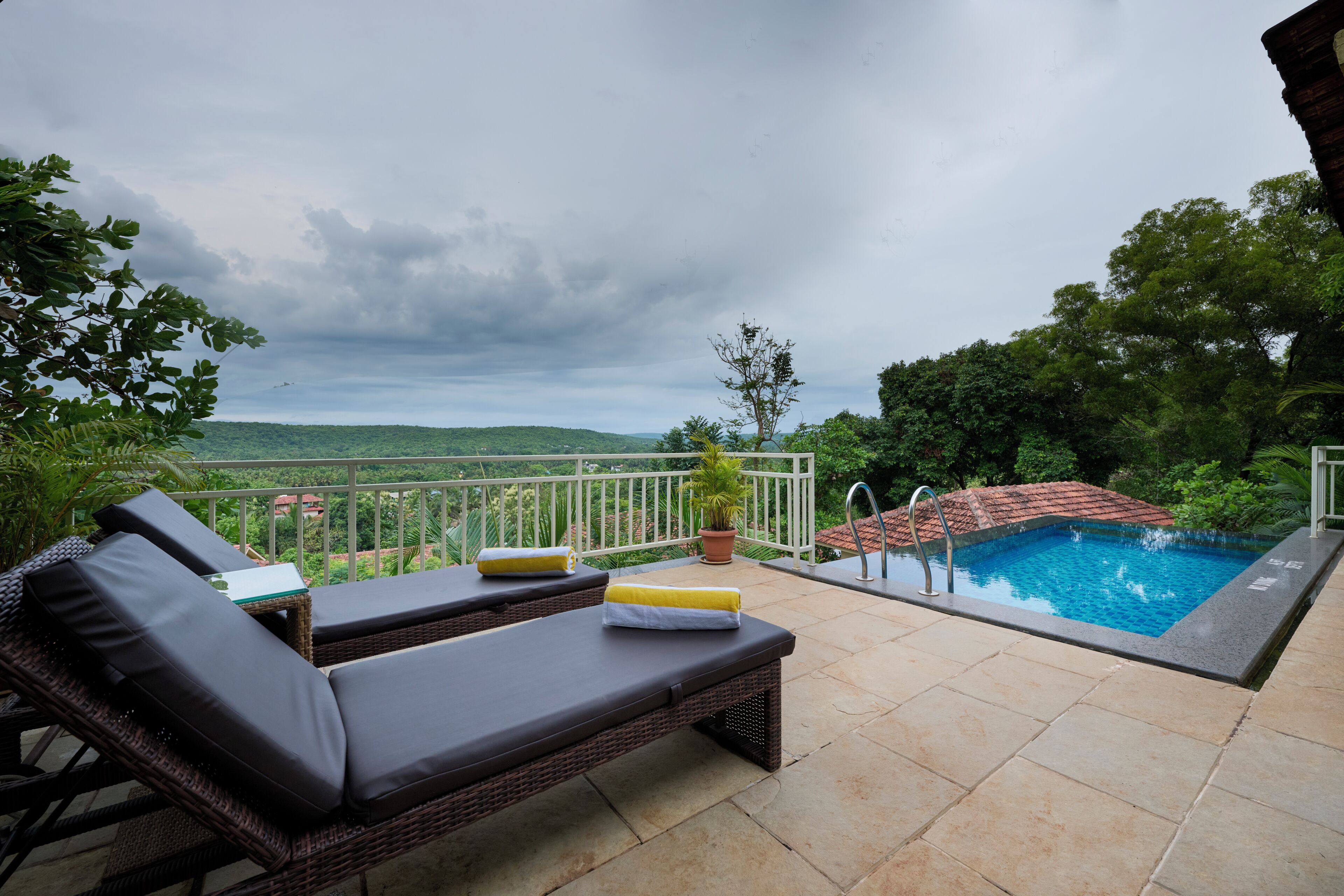 A rooftop pool area with lounge chairs and a view of the landscape.