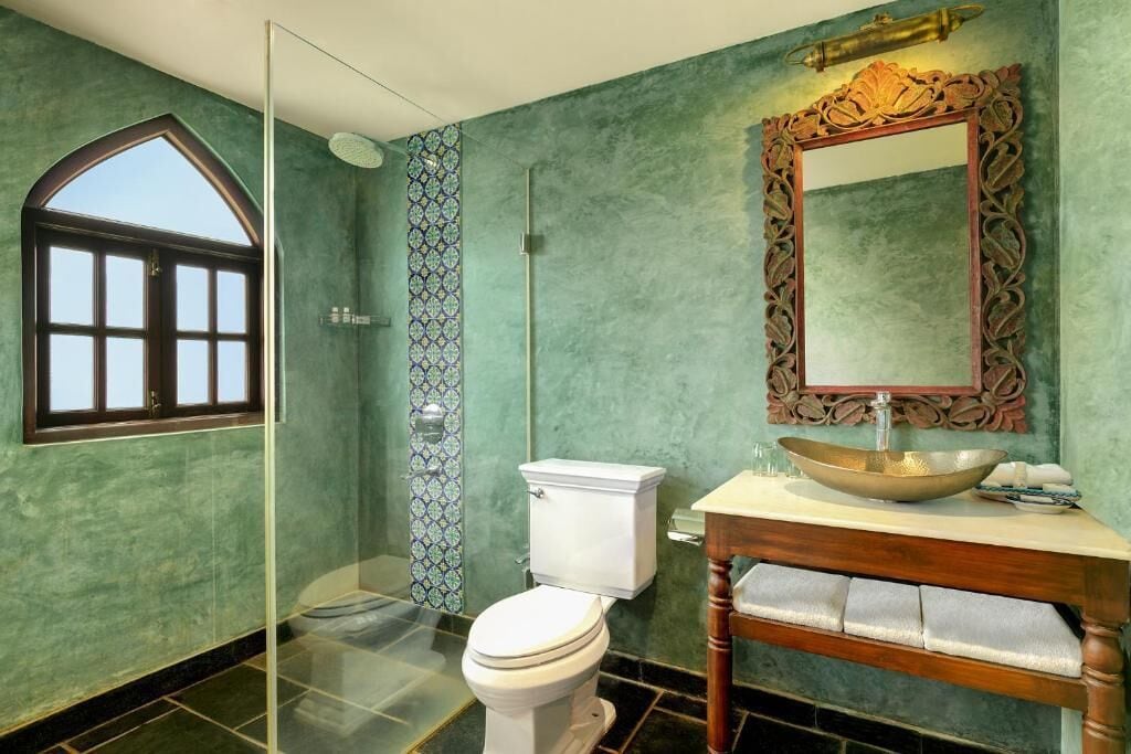 A bathroom with a toilet, sink, and mirror.