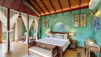 A bedroom with a bed, a ceiling fan, a window with curtains, and a wall with framed pictures.