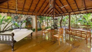Una habitación amplia con techo de madera, una cama, una mesa con sillas y un banco.