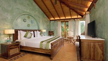 Una habitación de hotel con una cama de madera, un escritorio, un televisor y un ventilador de techo.