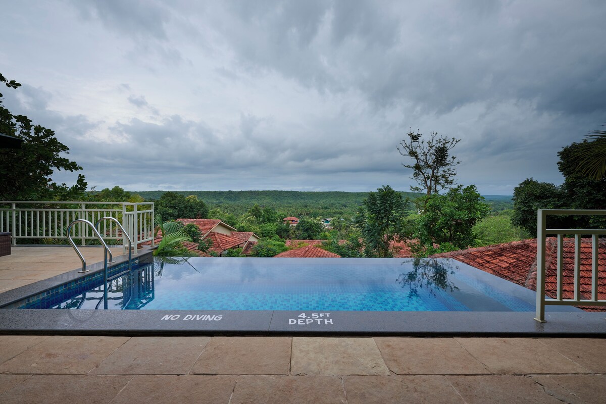An infinity pool with a no diving sign, 4.5 ft depth, and a view of a village.