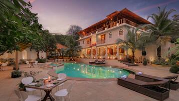 Relax by the spacious pool surrounded by lush greenery and comfortable seating.